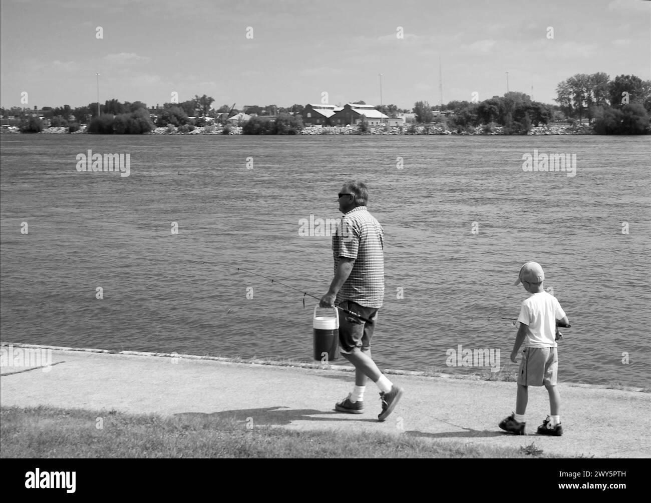 Père et fils transportant des engins de pêche le long de la rivière Niagara Falls, Canada, partageant ensemble un moment tranquille en plein air. Banque D'Images