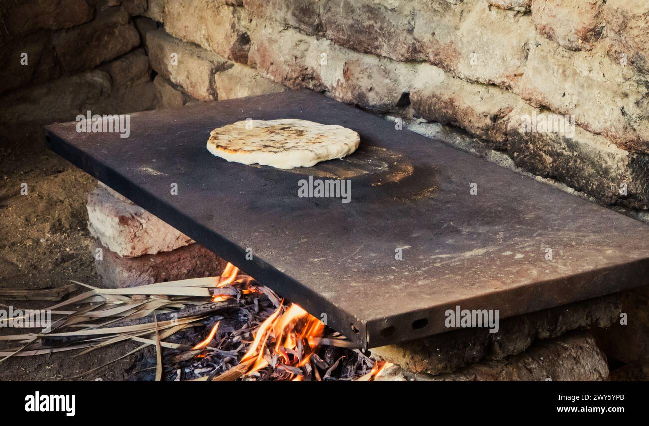 Cuisine du pain plat égyptien sur le poêle ouvert dans la cuisine extérieure d'un agriculteur Banque D'Images