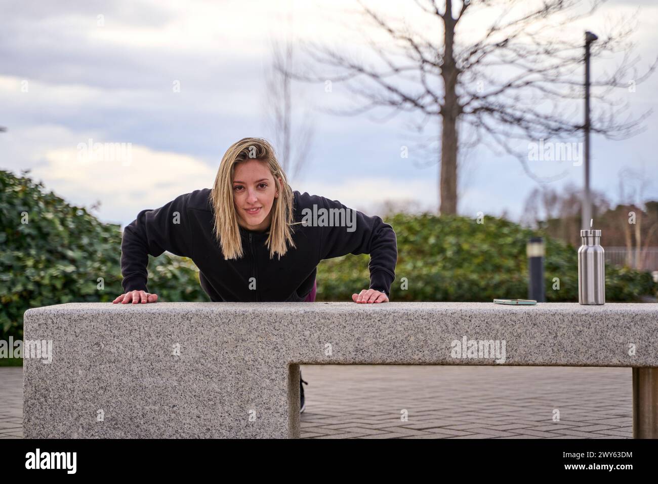 jeune athlète féminine faisant des pompes sur un banc. entraînement dans la rue. Banque D'Images