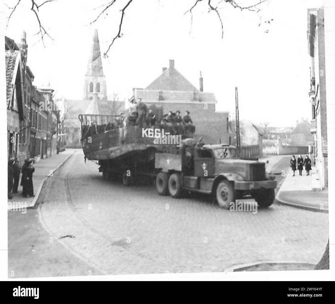 Les embarcations de débarquement sont transportées sur un véhicule routier traversant un village à des fins de déploiement. Banque D'Images