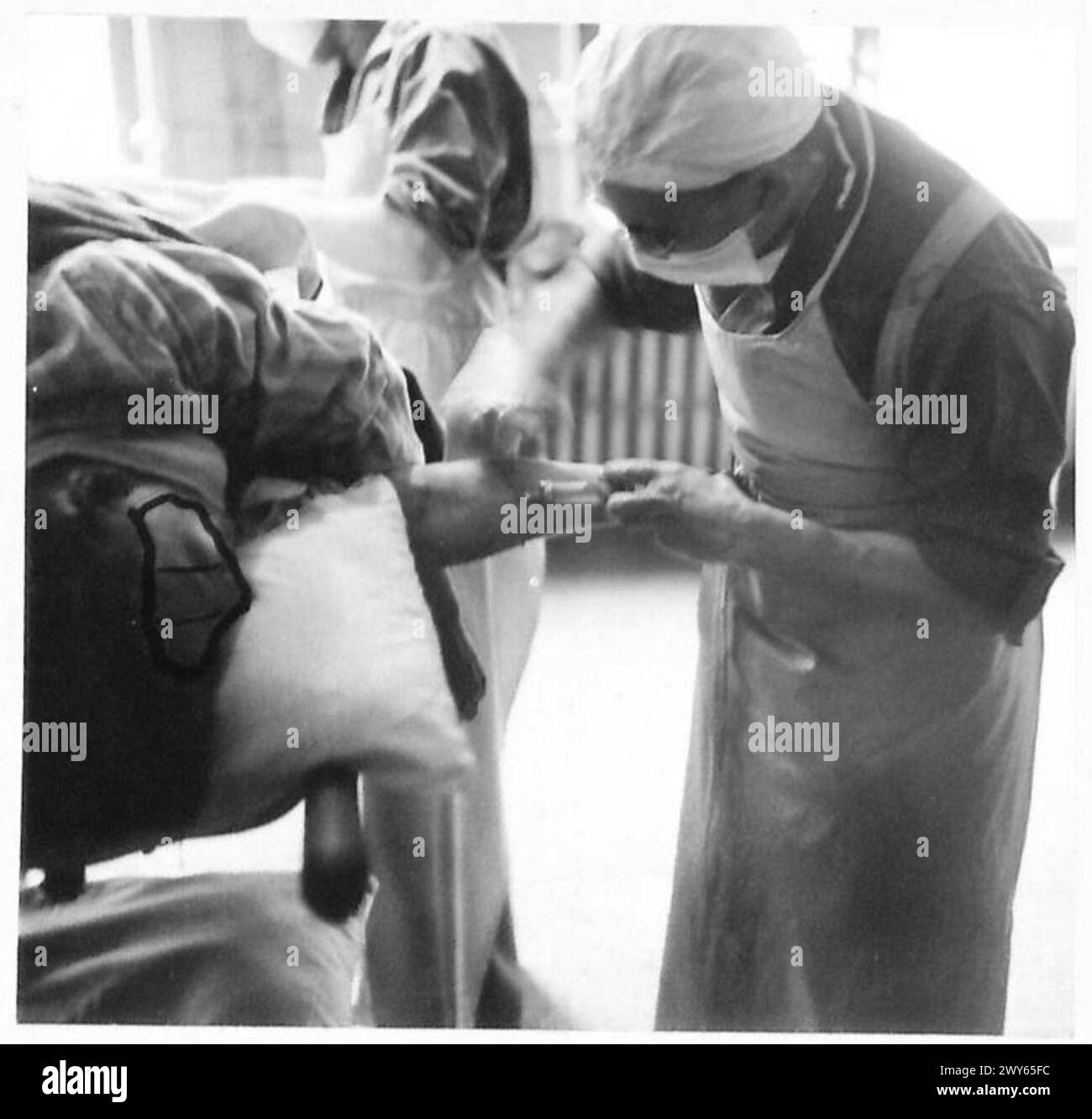 Une opération chirurgicale sur un patient dont la jambe est gravement endommagée par des éclats d’obus, impliquant une anesthésie, un nettoyage de plaie, l’ablation d’éclats d’obus, une injection de pénicilline, et l'habillage par le personnel médical. Banque D'Images