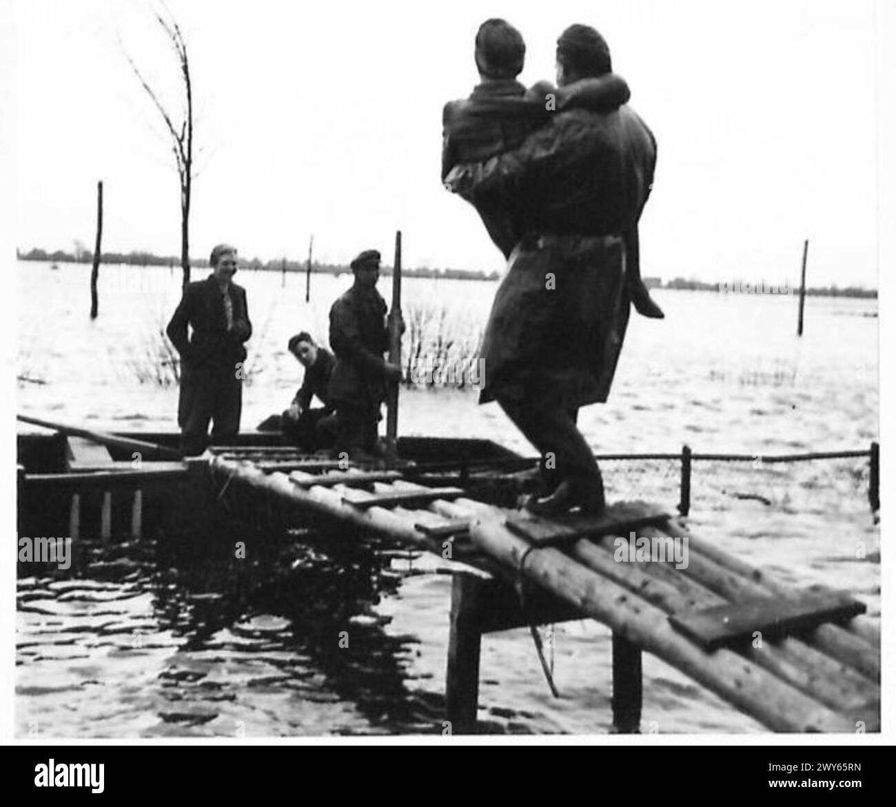 L'ÎLE INONDÉE DE WALCHEREN - soldat transporte une femme au bateau d'attente à travers le pont temporaire construit de la porte d'entrée à la porte. , Armée britannique, 21e groupe d'armées Banque D'Images