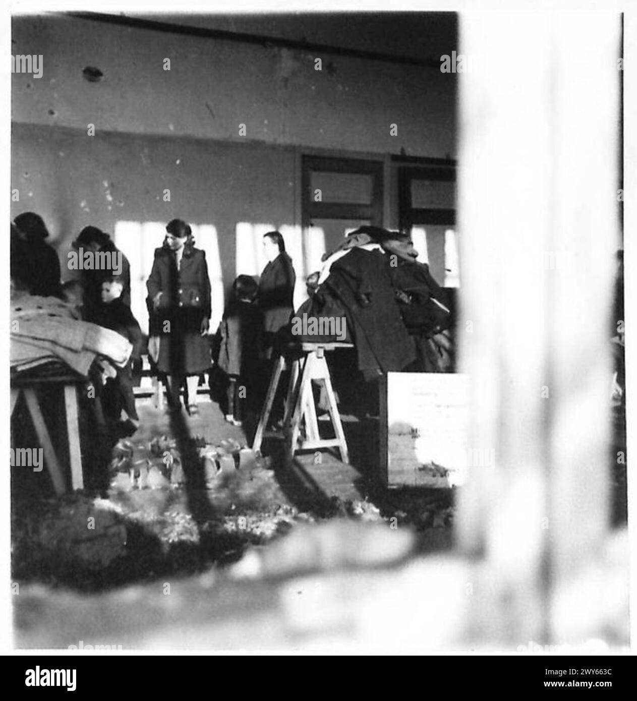 Le personnel allié distribue des vêtements pour les civils hollandais à travers des fenêtres brisées dans un bâtiment, British Army, 21st Army Group. Banque D'Images