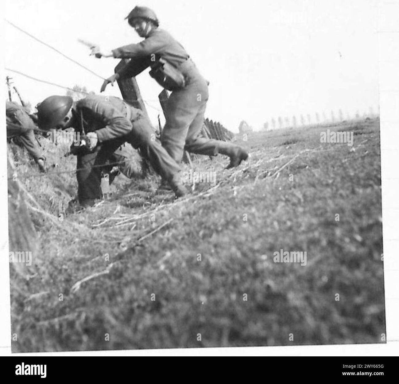 Des fantassins sont vus grimper au-dessus d'une clôture pendant les opérations de l'armée britannique sous le 21e groupe d'armées. Banque D'Images
