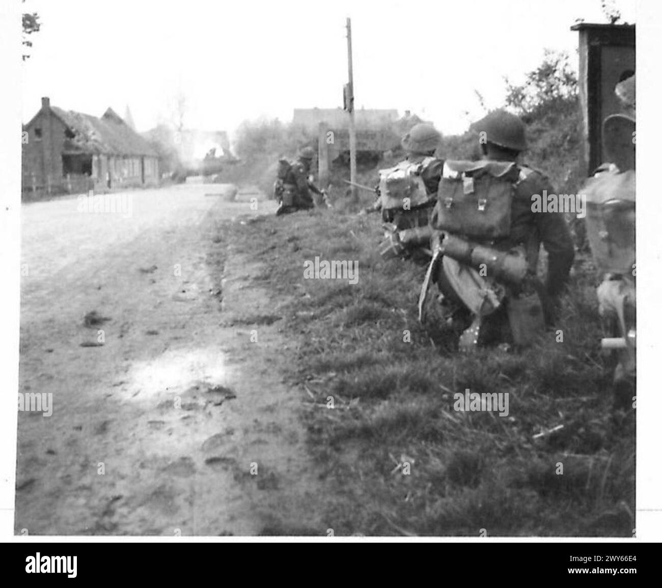 La 5e division avance vers Lubeck avec des troupes soutenues par des chars, tandis que les maisons du village brûlent en arrière-plan. Banque D'Images