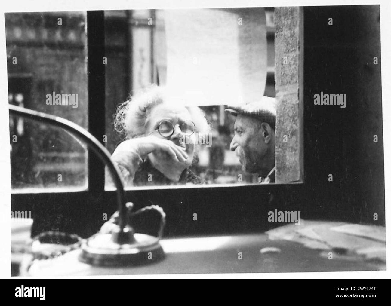 Une personne lit un journal gratuit affiché dans une vitrine, distribué pendant la période d'après-guerre par l'armée britannique. Banque D'Images