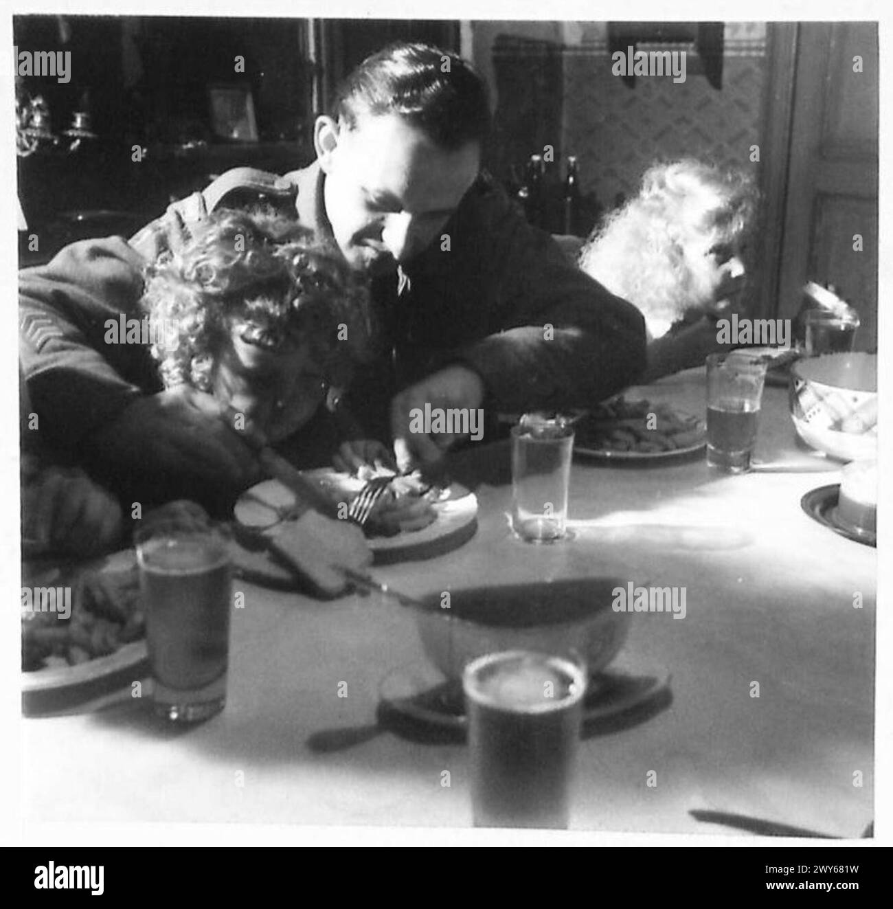 Charlie, fils du bourgmestre, est assis à côté d'un soldat britannique à l'heure du repas, illustrant les relations positives entre les soldats et les civils locaux, armée britannique, 21e groupe d'armées. Banque D'Images