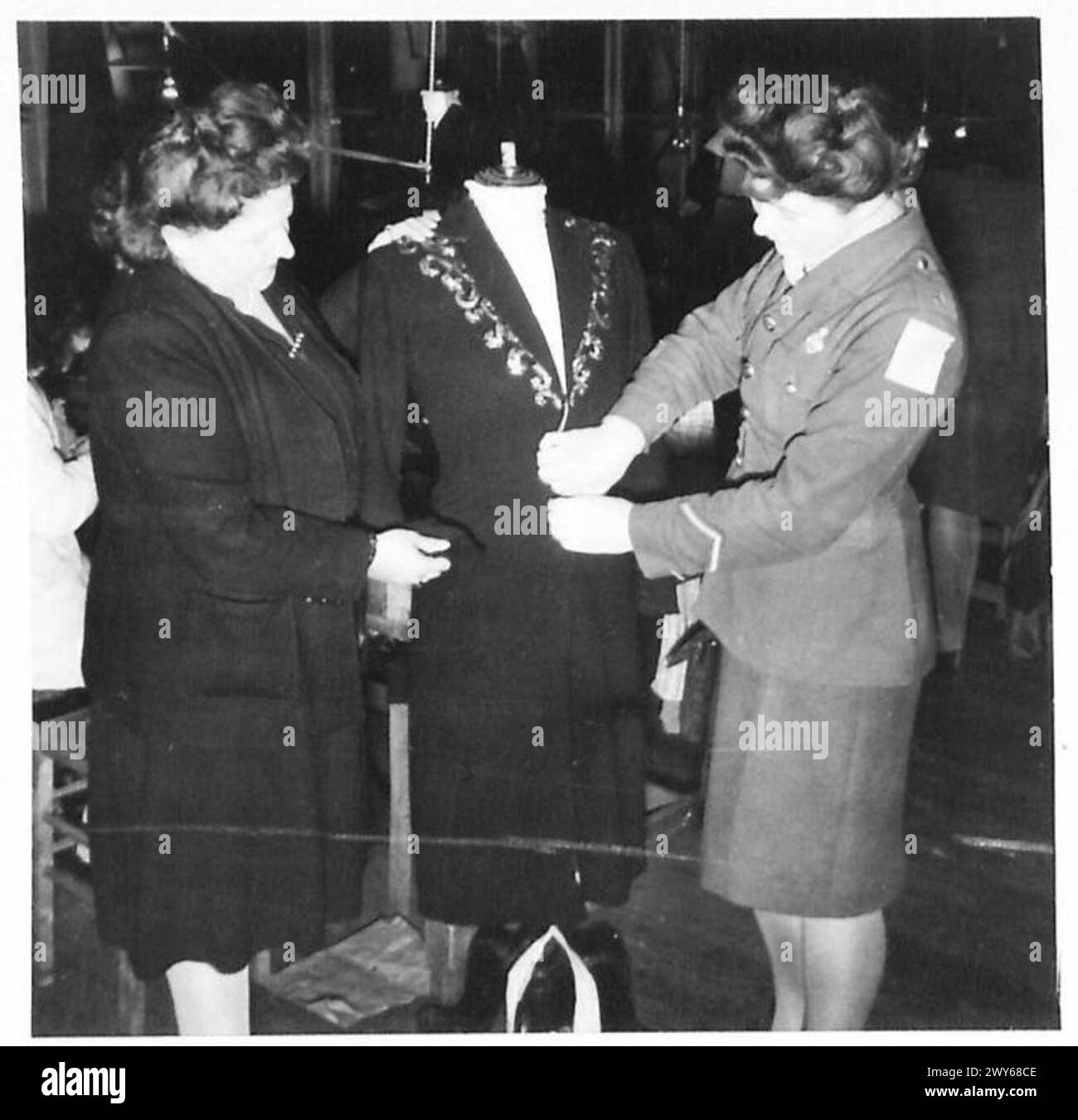 Des filles britanniques de service assistent à un défilé de mode à Paris, avec une fille examinant un modèle de vêtements presque terminé. Banque D'Images