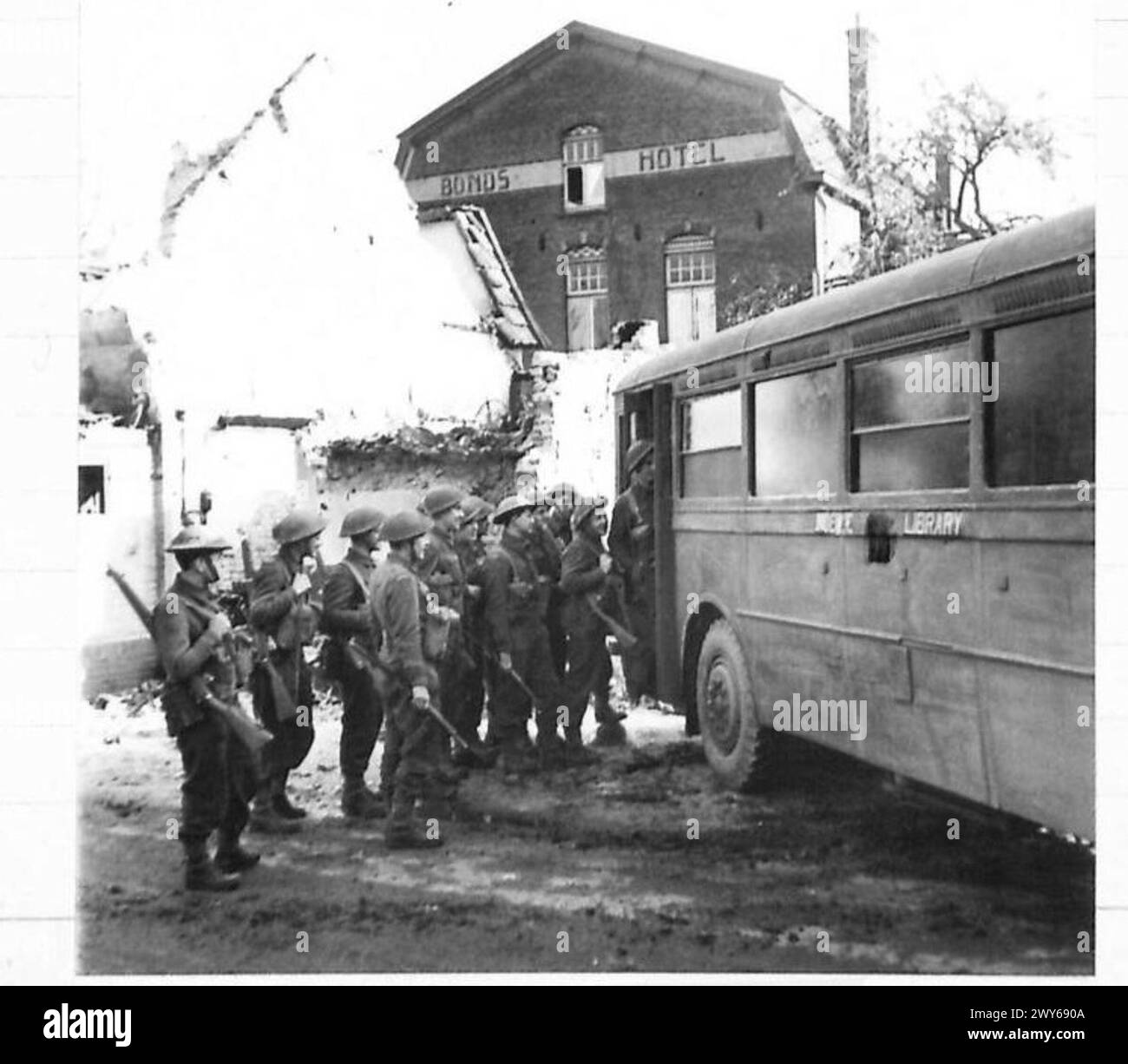 BIBLIOTHÈQUE MOBILE - faire la queue pour des livres dans le village de Mock où les 53 Dorsets sont stationnés. Les bâtiments endommagés de ce village de première ligne peuvent être vus en arrière-plan. , Armée britannique, 21e groupe d'armées Banque D'Images