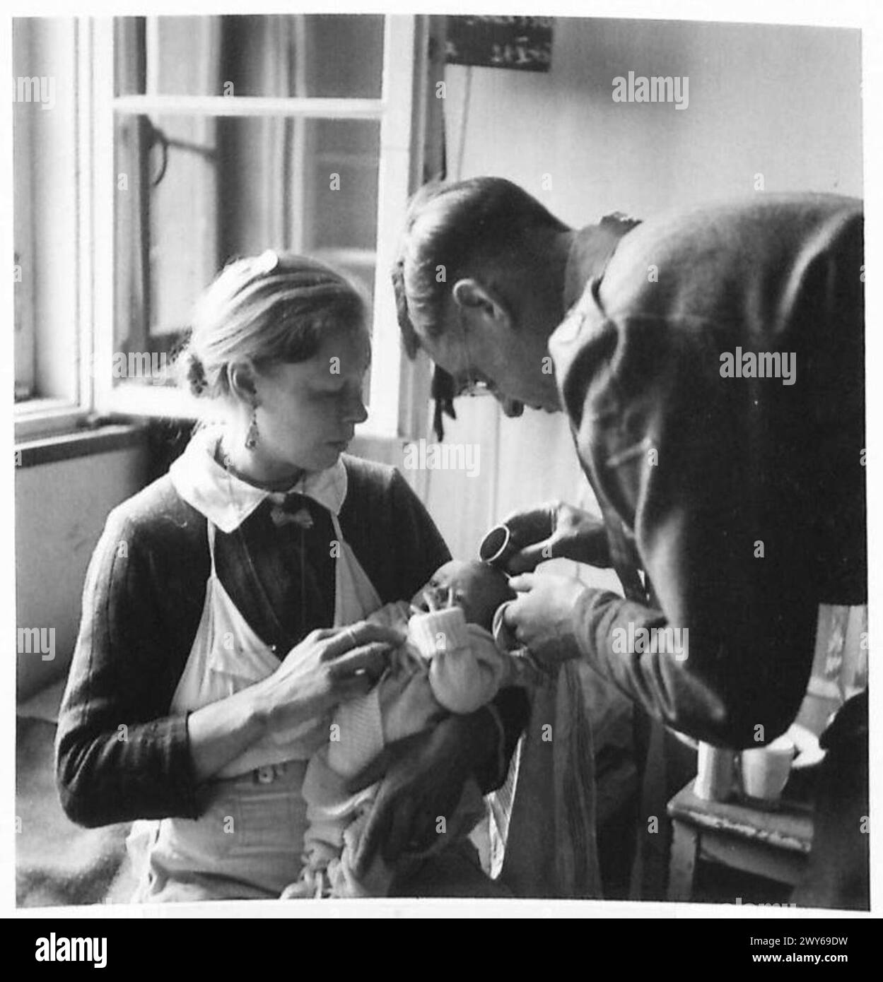 Olga Lisenko de Tsernigov, Ukraine, tient son nouveau-né alors que le père Fay le baptise Tamara au camp de Belsen sous la supervision de l'armée britannique, 21e groupe d'armées. Banque D'Images