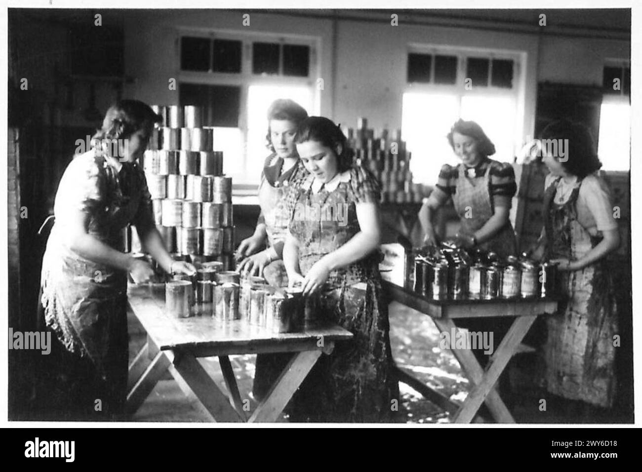 Lors de l'évacuation des civils de l'Allemagne occupée par les Britanniques, des filles allemandes sont vues préparer de la nourriture en ouvrant des conserves de pommes de terre dans les cuisines, observé par l'armée britannique, 21e groupe d'armées. Banque D'Images