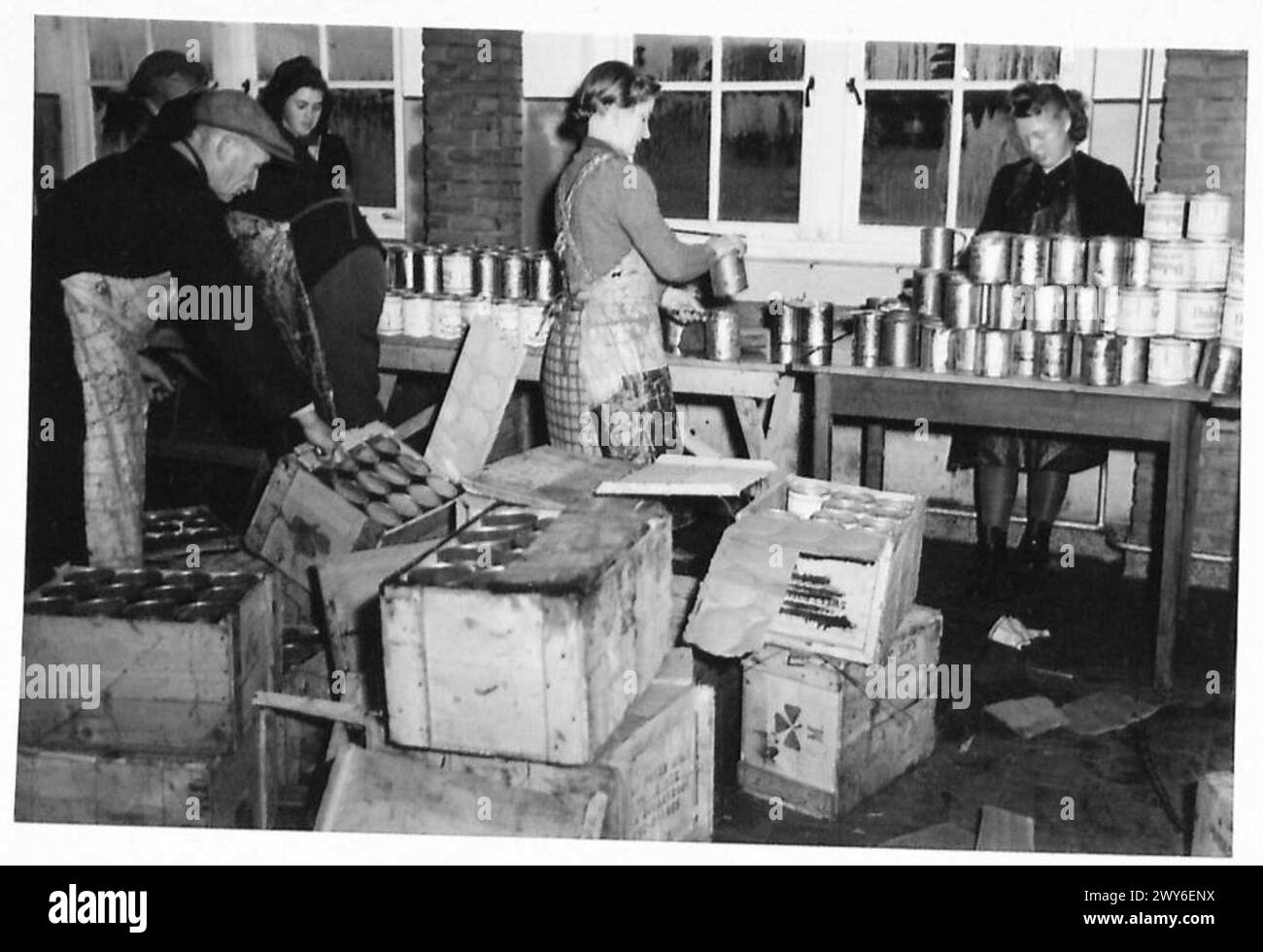 Les civils allemands ouvrent des conserves de nourriture dans les cuisines lors de l'évacuation des zones occupées par les Britanniques, illustrant les opérations de secours et de soutien civil d'après-guerre, armée britannique, 21e groupe d'armées. Banque D'Images