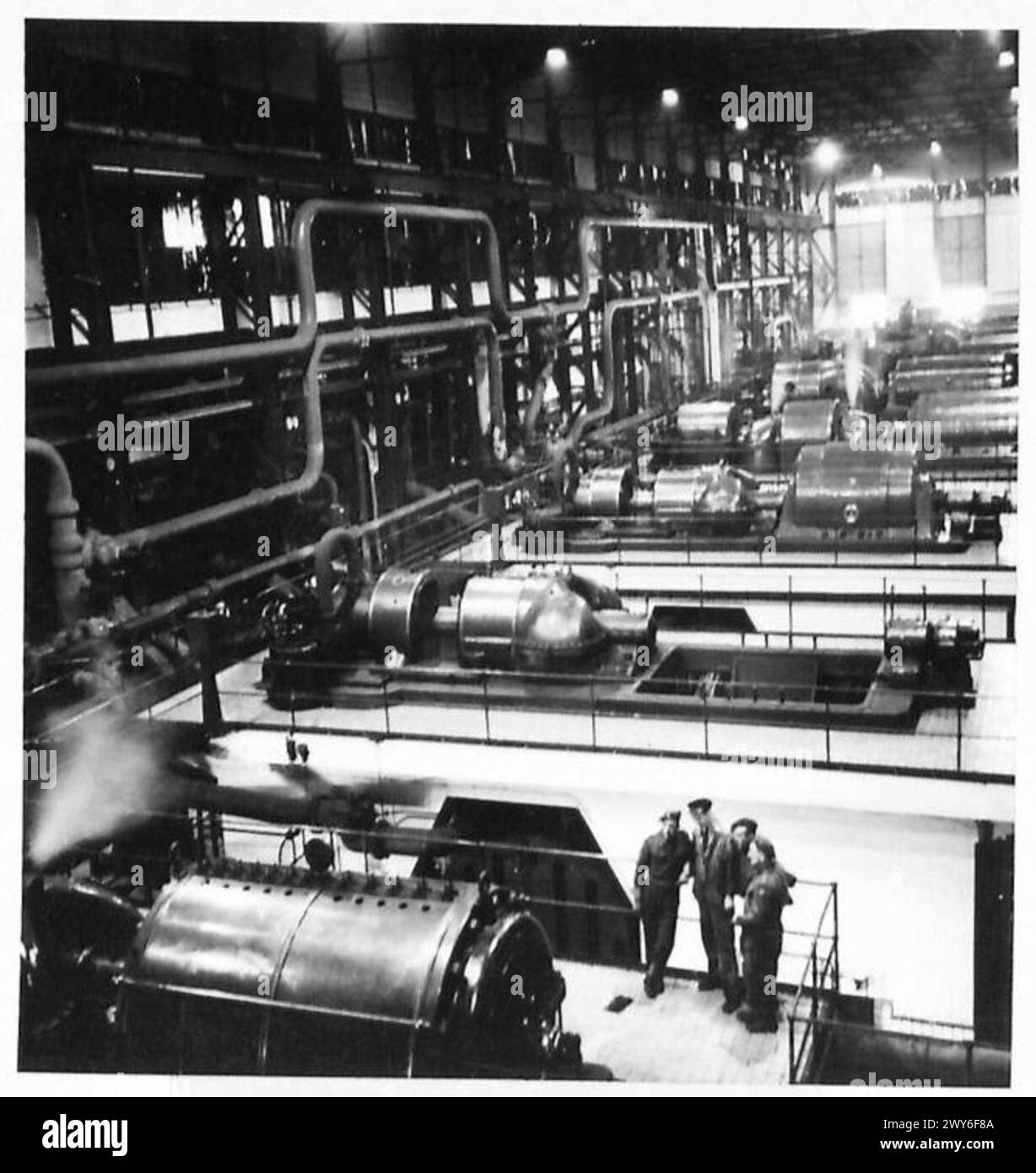 Trois soldats britanniques visitent une mine de charbon en Hollande, debout à l'intérieur de la centrale électrique à côté de grands moteurs et générateurs, documentés par l'armée britannique, 21e groupe d'armées. Banque D'Images