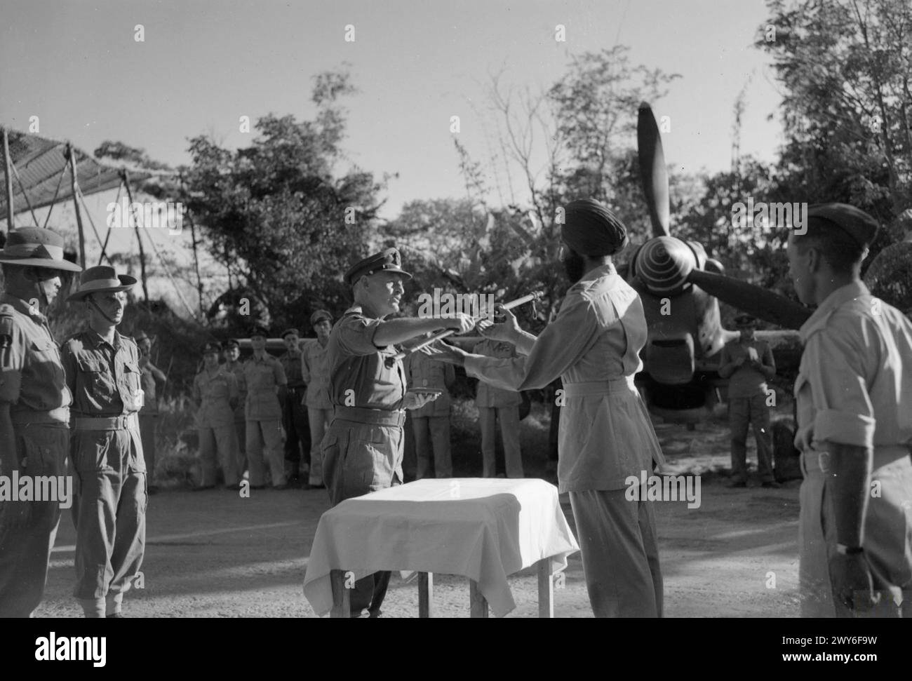 En Birmanie, en 1944, le major-général D.D. Gracey de la 20e division indienne présente une épée japonaise capturée au chef d'escadron Arban Singh d'un escadron de l'armée de l'air indienne sur une piste d'atterrissage avancée. Banque D'Images