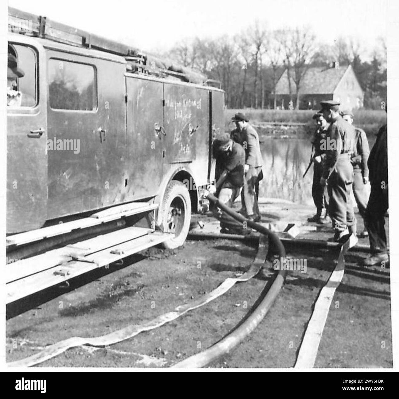 Les civils allemands utilisent des tuyaux des moteurs pour combattre un incendie de décharge de charbon, démontrant la réponse d'urgence et la défense civile dans des conditions de guerre. Banque D'Images