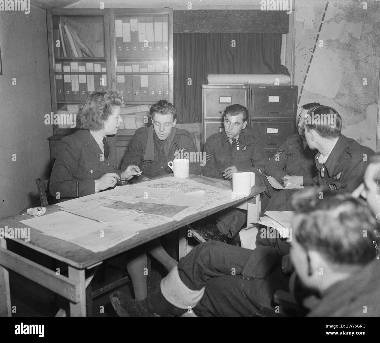 COMMANDEMENT DES BOMBARDIERS DE LA ROYAL AIR FORCE, 1942-1945. - Un officier de renseignement de la WAAF, l'officier de section P Duncalfe, interroge le pilote, l'adjudant H Blunt (à sa gauche), et l'équipage de l'Avro Lancaster B Mark III, JB362 'EA-d', ('d pour Donald') du No. 49 Squadron RAF, à leur retour à Fiskerton, Lincolnshire, d'un raid de bombardement sur Berlin, Allemagne. Lors de leur sortie suivante vers Berlin cinq jours plus tard, Blunt et son équipage sont abattus en « d for Donald » et tués. , Royal Air Force, Royal Air Force Regiment, Sqdn, 49, Royal Air Force, Women's Auxiliary Air Force Banque D'Images