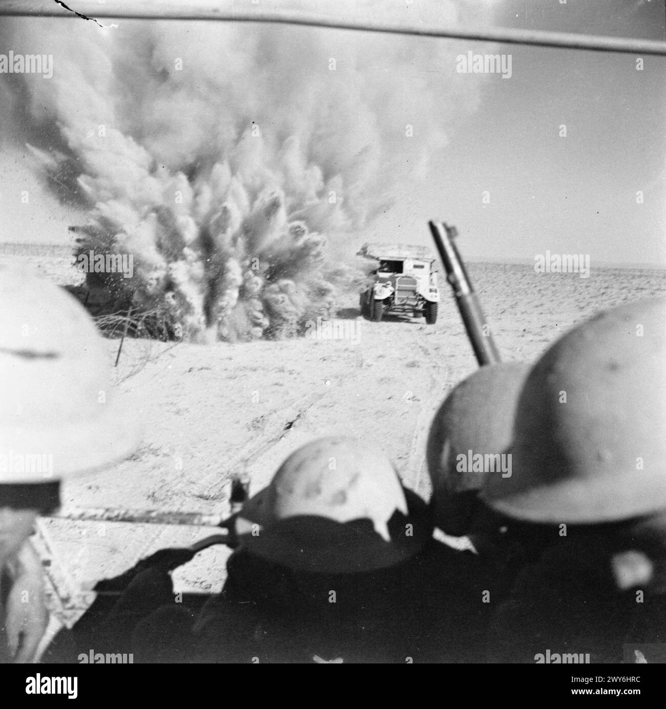 Lors de la bataille d'El Alamein en 1942, un camion britannique transportant de l'infanterie passe près d'une mine en explosion tout en avançant à travers des champs de mines ennemis et des câbles vers les lignes de front en Afrique du Nord. Banque D'Images