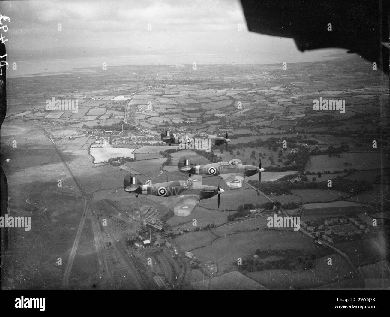 ROYAL AIR FORCE FIGHTER COMMAND, 1939-1945. - Trois Hawker Hurricane Mark IIBs du No 79 Squadron RAF basé à Fairwood Common, Glamorgan, volant en formation 'vic' au-dessus du sud du pays de Galles. Les pilotes étaient, le commandant, chef d'escadron G d Haysom (avion de tête, Z3745 'NV-B'), et ses commandants de vol, Flight Lieutenant R P Beamont (avion le plus proche, Z2633 'NV-M'), et Flight Lieutenant l T Bryant-Fenn (avion le plus éloigné, Z3156 'NV-F). , Beamont, Roland Prosper, Royal Air Force, Royal Air Force Regiment, Sqdn, 79 Banque D'Images