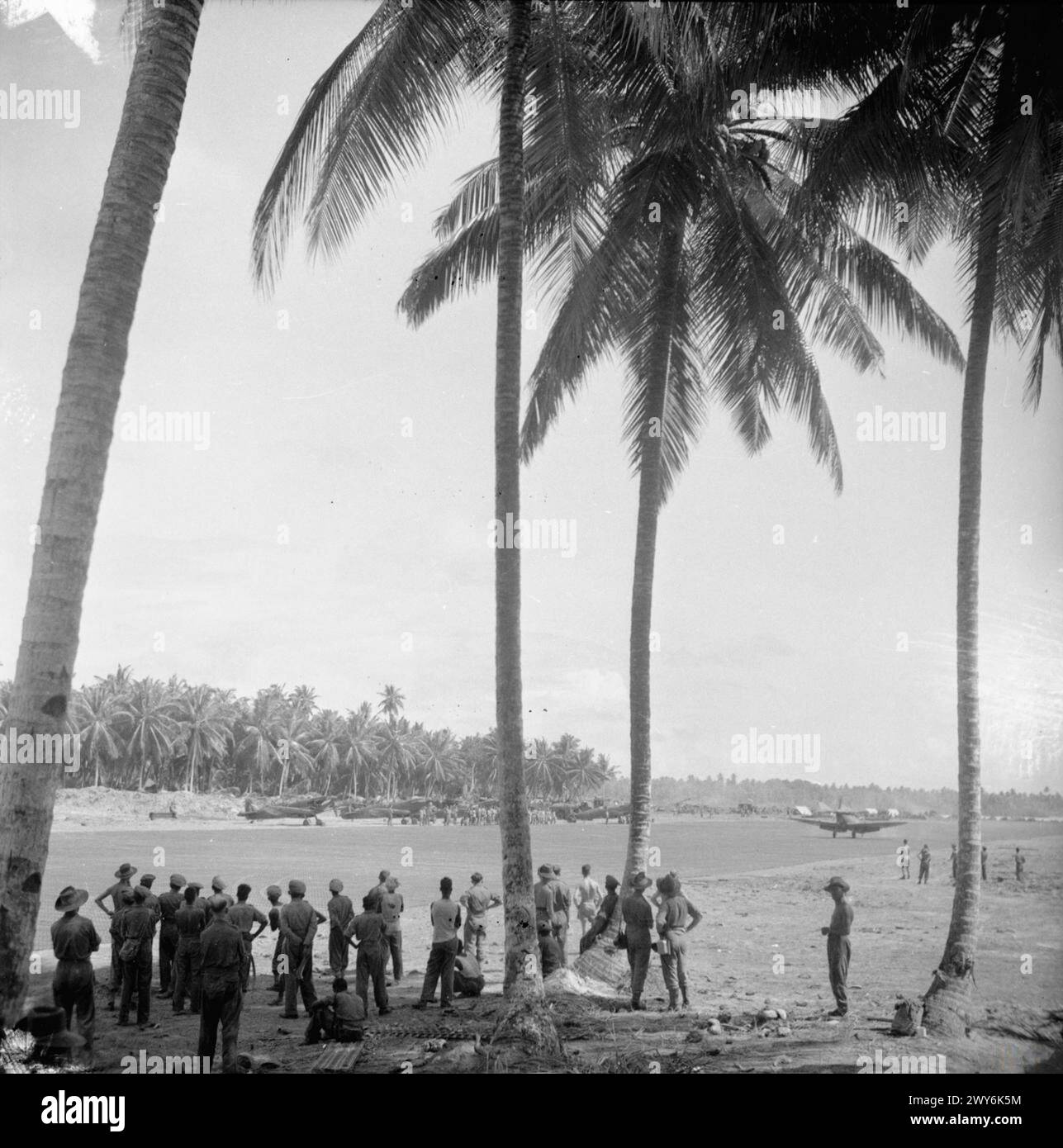 OPÉRATIONS DE LA ROYAL AIR FORCE EN EXTRÊME-ORIENT, 1941-1945. - Les hommes du corps des pionniers indiens et les travailleurs civils engagés dans la construction de la piste d'atterrissage sur Brown's West Island, aux îles Cocos, s'arrêtent pour regarder le premier décollage de la base, par le Supermarine Spitfire Mark VIIIs du No. 136 Squadron RAF. il restait 300 verges de piste à terminer à l'époque. , Armée indienne, Indian Pioneer corps, Royal Air Force, 136e escadron Banque D'Images