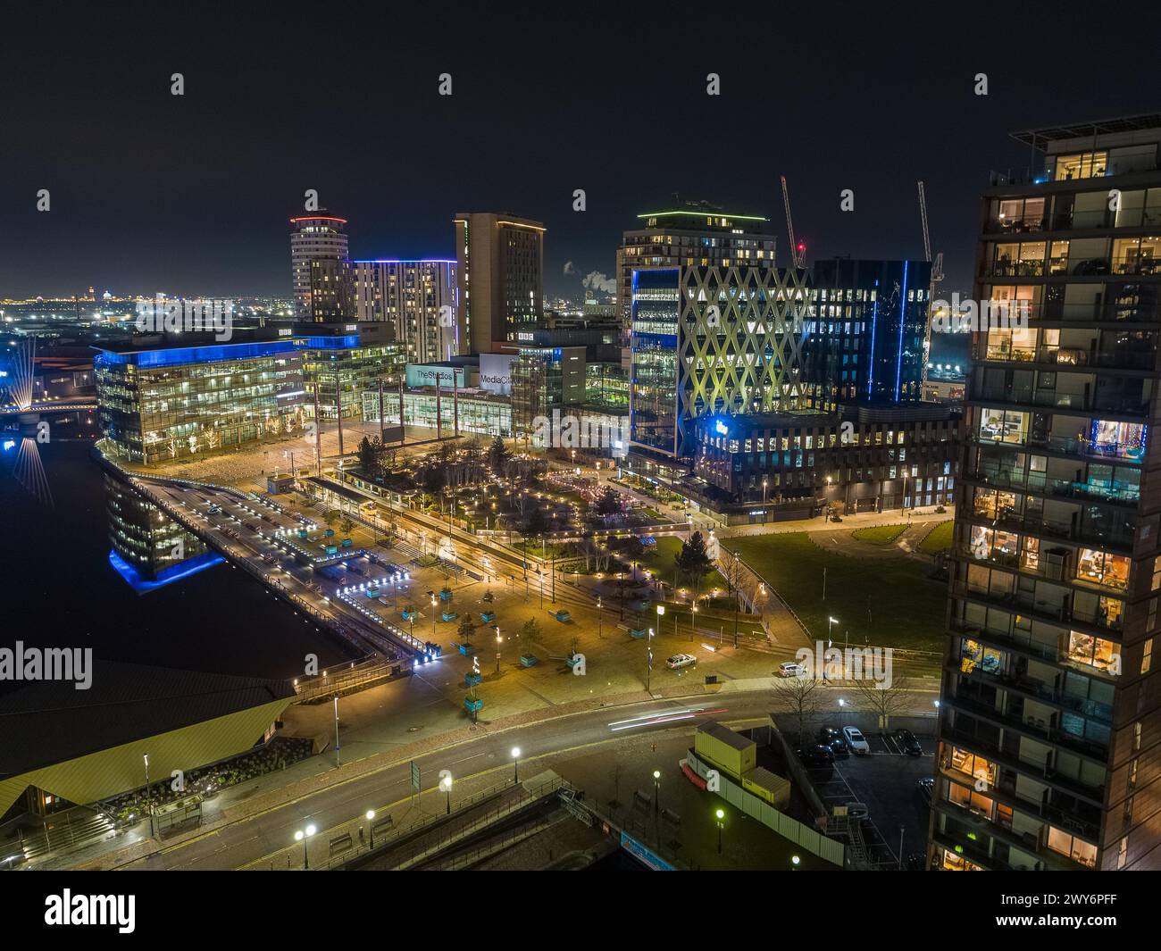 Photographie nocturne par drone à MediaCityUK, Salford Quays, y compris les BBC Studios, l'Université de Salford et le Dock 10 au premier plan Banque D'Images
