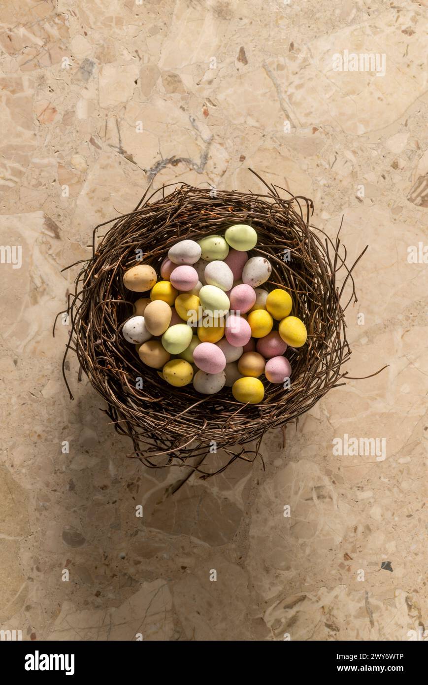 Vue en plan de mini-œufs enrobés de sucre colorés disposés dans un faux nid d'oiseau. Banque D'Images