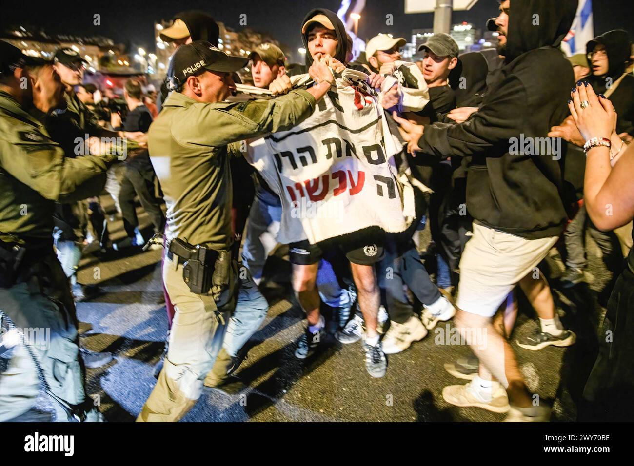 Un soldat de la police des frontières israélienne repousse les manifestants portant une pancarte pour la libération de l'otage israélo-américain Hersh Goldberg Polin pendant la manifestation. Plus de 80 000 Israéliens se sont rassemblés autour de la Knesset pour protester contre le premier ministre Benjamin Netanyahu, exigeant un accord immédiat sur les otages et des élections générales. Des affrontements avec la police israélienne ont eu lieu lors d'un barrage routier sur l'autoroute Begin par des manifestants qui ont allumé des feux de joie et des torches, et ils ont été dispersés par des canons à eau mouffettes de la police. Banque D'Images