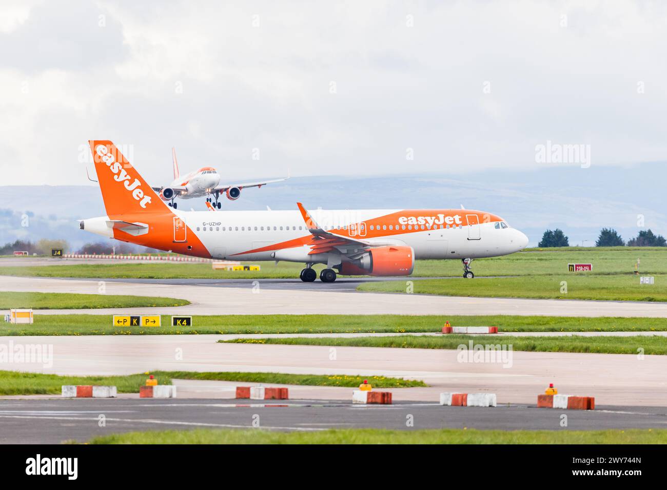 Deux Airbus A320 EasyJet photographiés à l'aéroport de Manchester le 4 avril 2024, l'un circulant pour le décollage et l'autre se préparant à atterrir. Banque D'Images