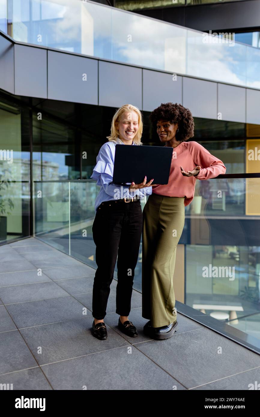 Deux femmes aux caractéristiques similaires se tiennent côte à côte, souriantes, devant la grande architecture. Banque D'Images