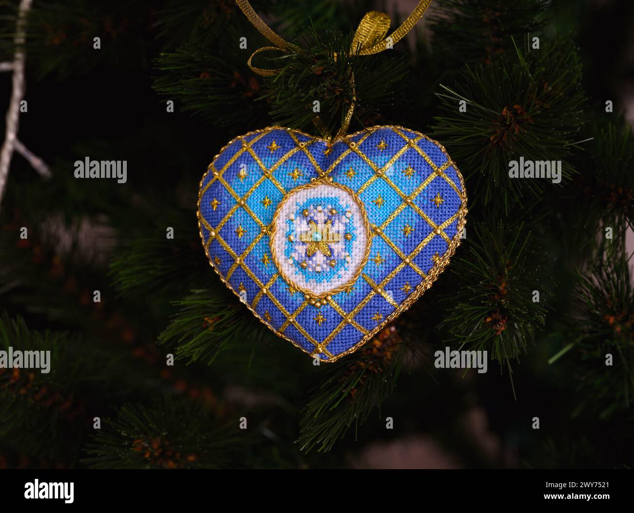 Un ornement d'élégance intemporelle de Noël point de croix bleu sur un sapin de Noël. Cet ornement de Noël bleu et or avec flocon de neige brodé et fou Banque D'Images