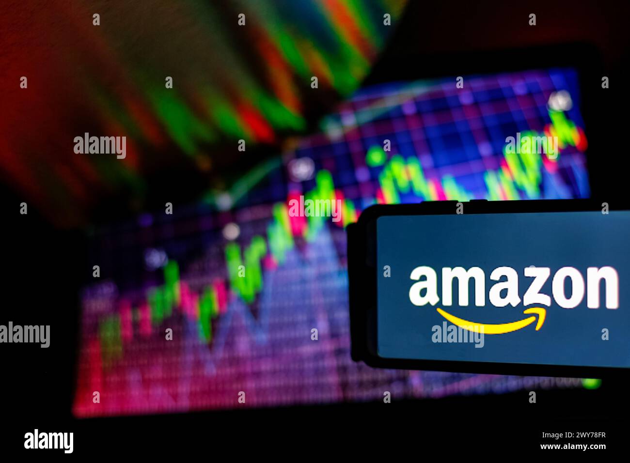 Dans cette illustration photo logo d'Amazon est vu sur un smartphone contre un écran affichant une illustration des marchés commerciaux. Banque D'Images