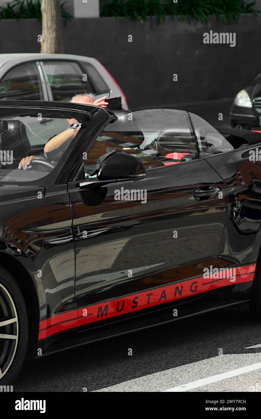 Tarragone, Espagne - 4 avril 2024 : une Mustang noire brille sous le soleil de Tarragone, ses détails rouges capturent l'œil tout en reflétant le a environnant Banque D'Images