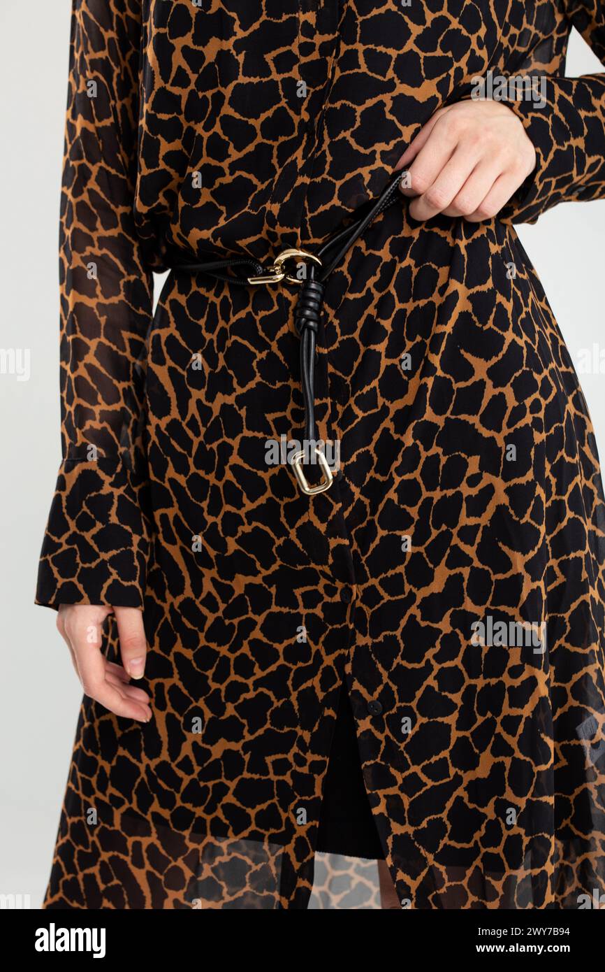 Mannequin affiche une robe chemise à imprimé girafe tendance avec ceinture noire. Parfait pour les sorties décontractées ou une soirée. Banque D'Images