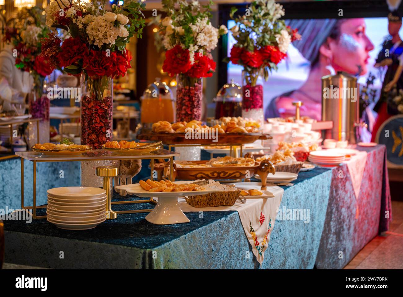 Une table joliment décorée est chargée d'une variété de délicieuses pâtisseries, de pain et de pièces maîtresses florales. Banque D'Images