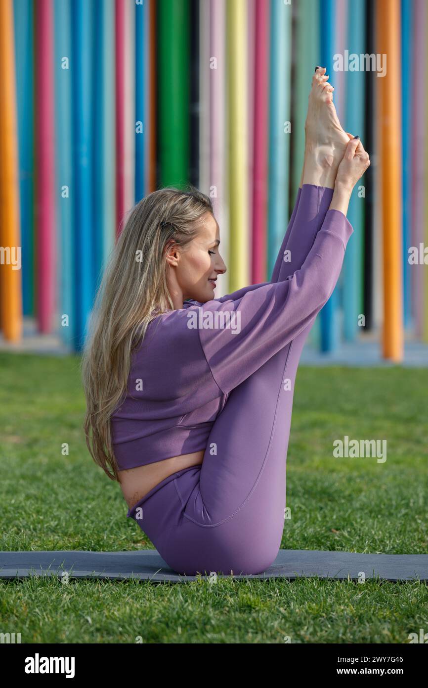 Une belle blonde femme modèle et professeur de yoga, faisant du yoga dans le parc CityLife, devant la sculpture Coloris, CityLife, Milan, Italie Banque D'Images