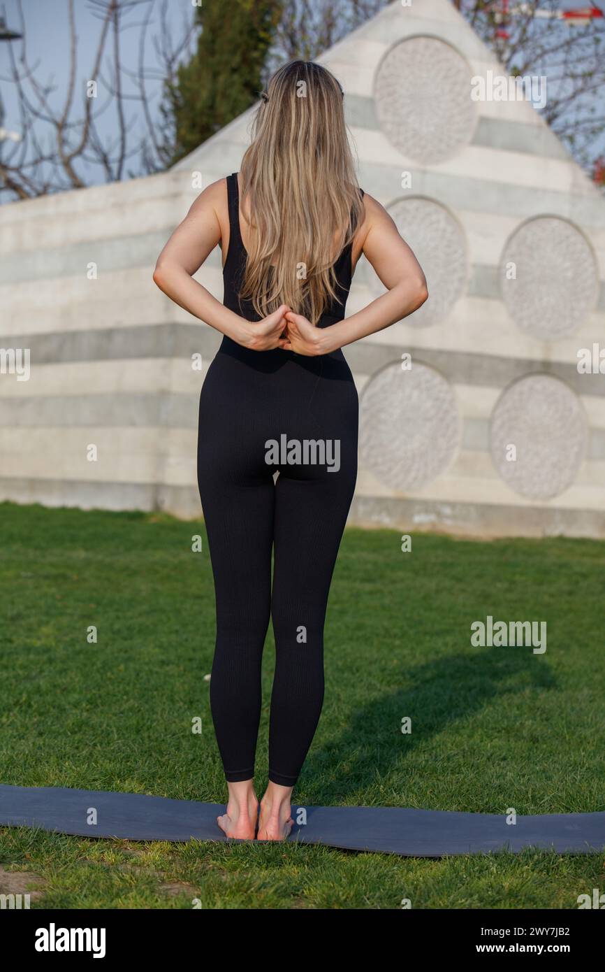 Une belle blonde femme modèle et professeur de yoga, faisant du yoga dans le parc CityLife, devant la sculpture Coloris, CityLife, Milan, Italie Banque D'Images