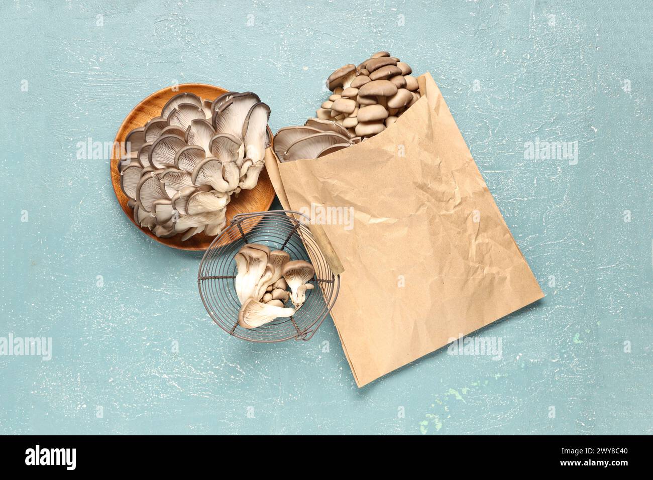 Planche en bois et sac en papier avec des champignons d'huître frais sur fond bleu Banque D'Images