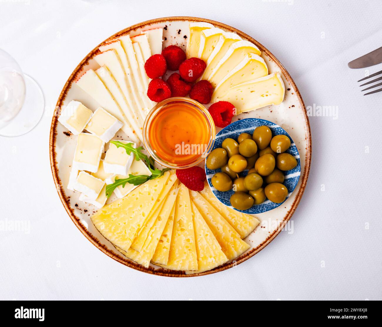 Différents types de fromage, miel, framboises et olives sur bois Banque D'Images