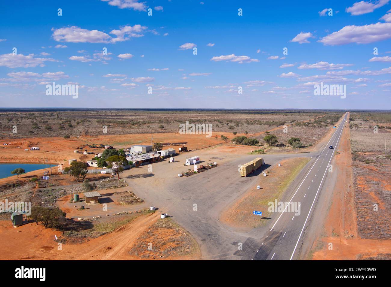 Vue aérienne d'une station-service éloignée avec une longue route droite à travers un paysage clairsemé Banque D'Images