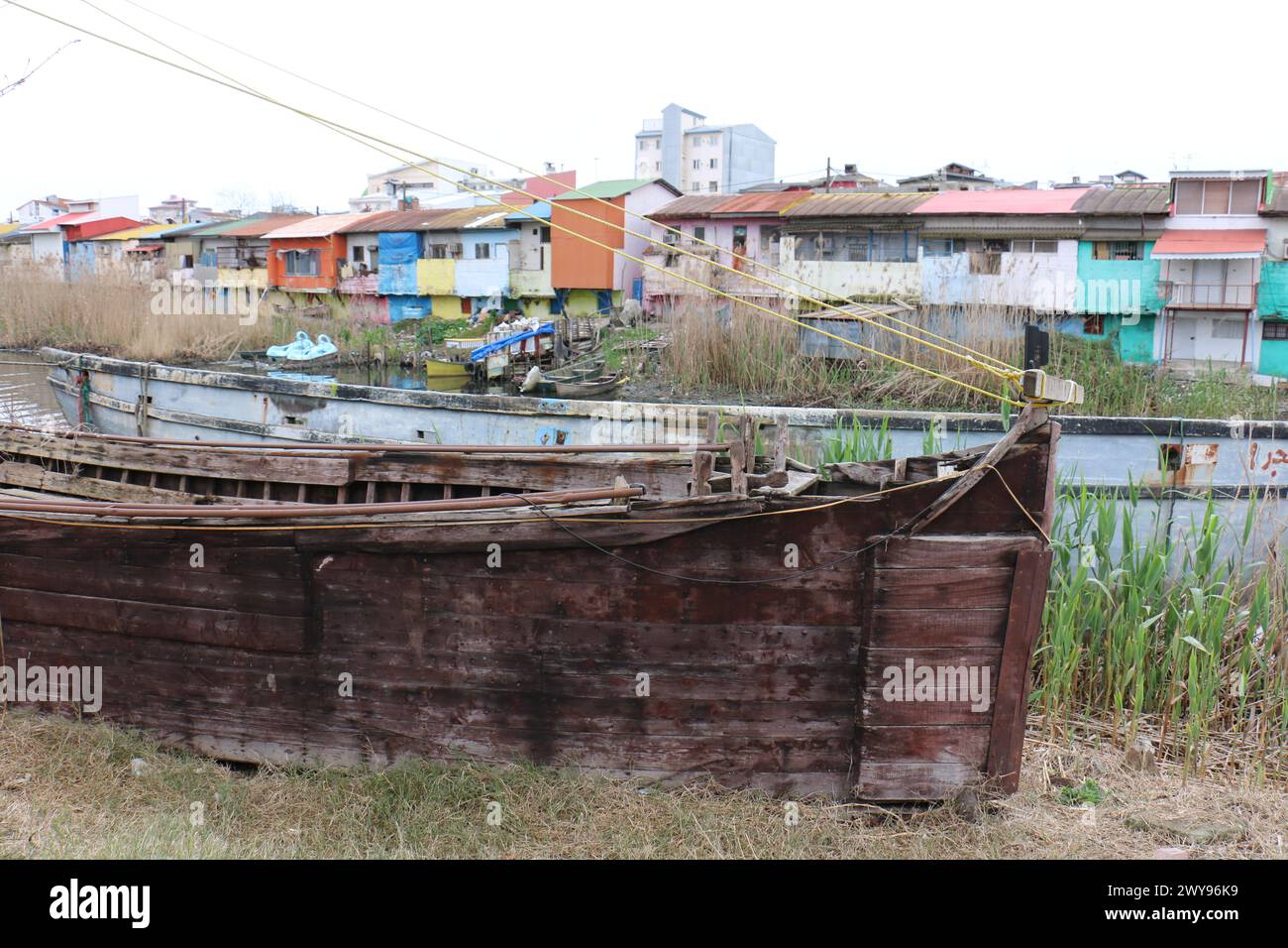 Un vieux bateau en bois cassé près d'Anzali Wetland Iran, en face de la maison colorée à côté de la lagune. Banque D'Images