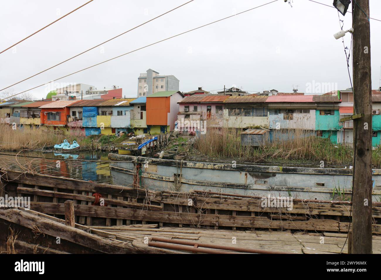 Un vieux bateau en bois cassé près d'Anzali Wetland Iran, en face de la maison colorée à côté de la lagune. Banque D'Images
