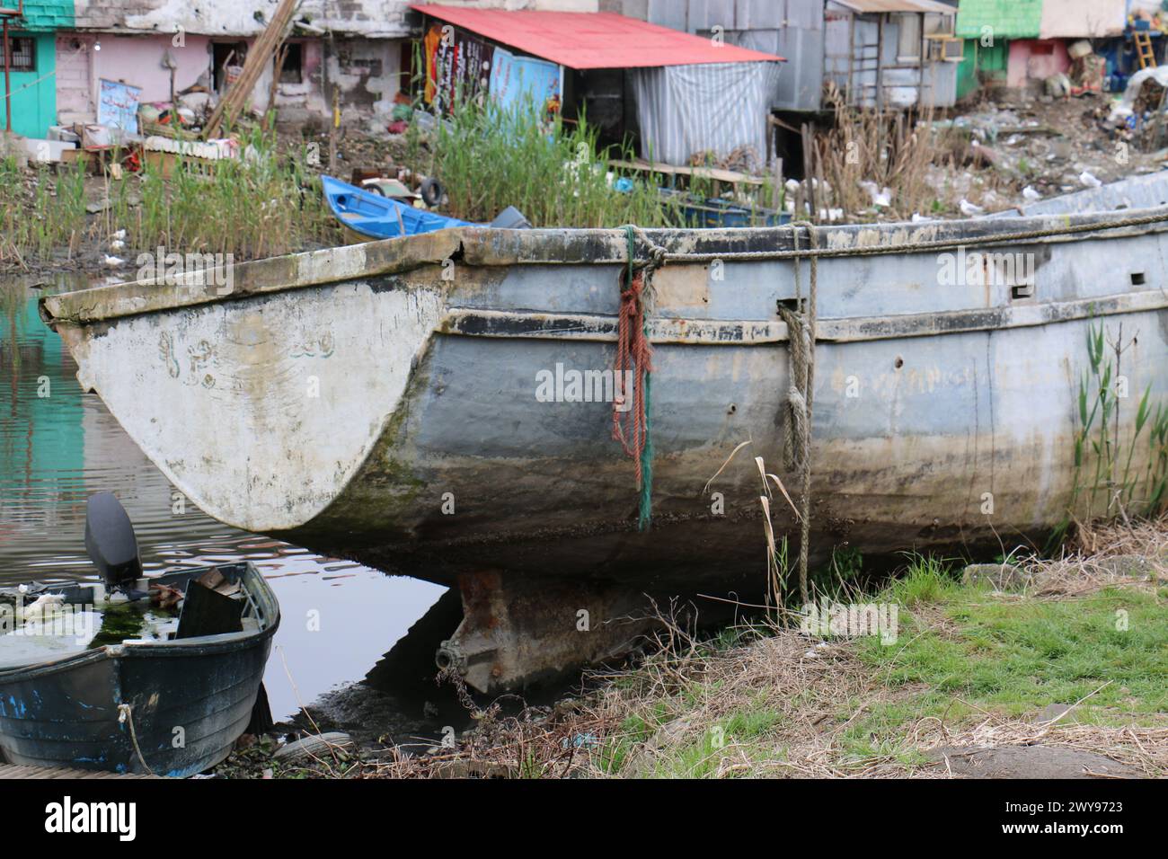 Un vieux bateau en bois cassé près d'Anzali Wetland Iran, en face de la maison colorée à côté de la lagune. Banque D'Images