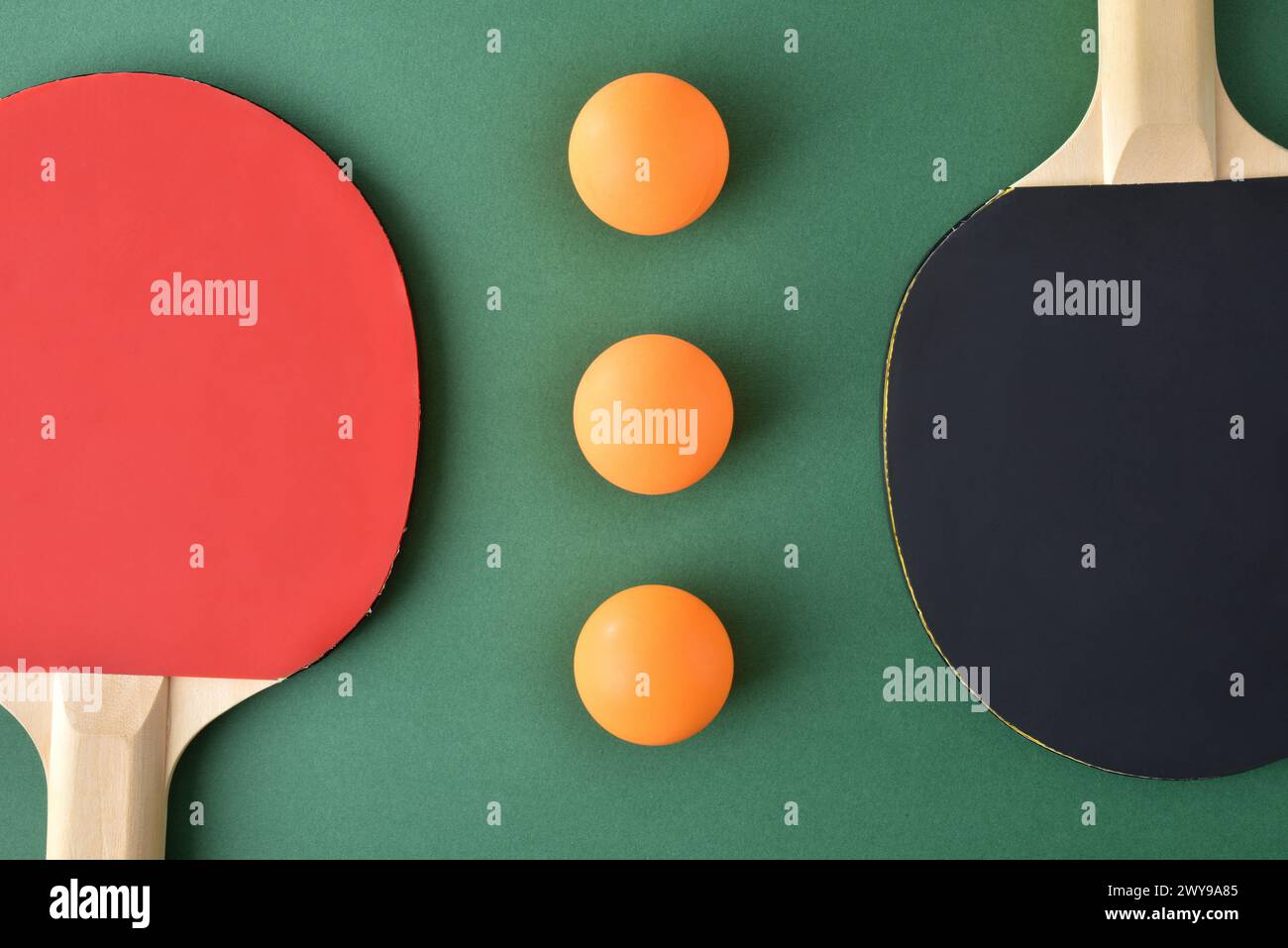 Composition avec jeu de pagaies de ping-pong et trois boules orange sur une table de jeu verte. Vue de dessus. Banque D'Images