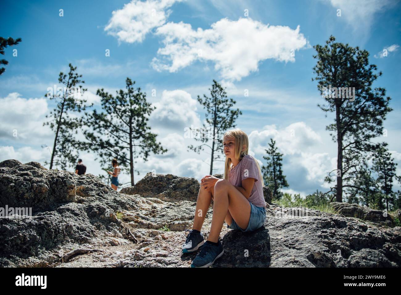 Adolescente assise sur des rochers dans la scène de la nature l'après-midi d'été Banque D'Images