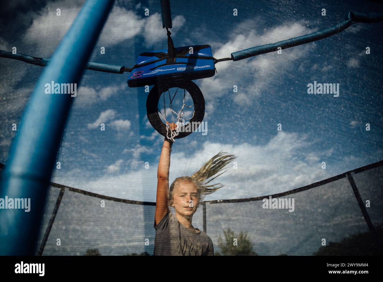 Preteen girl jouant au basket-ball sur trampoline en plein air en été Banque D'Images
