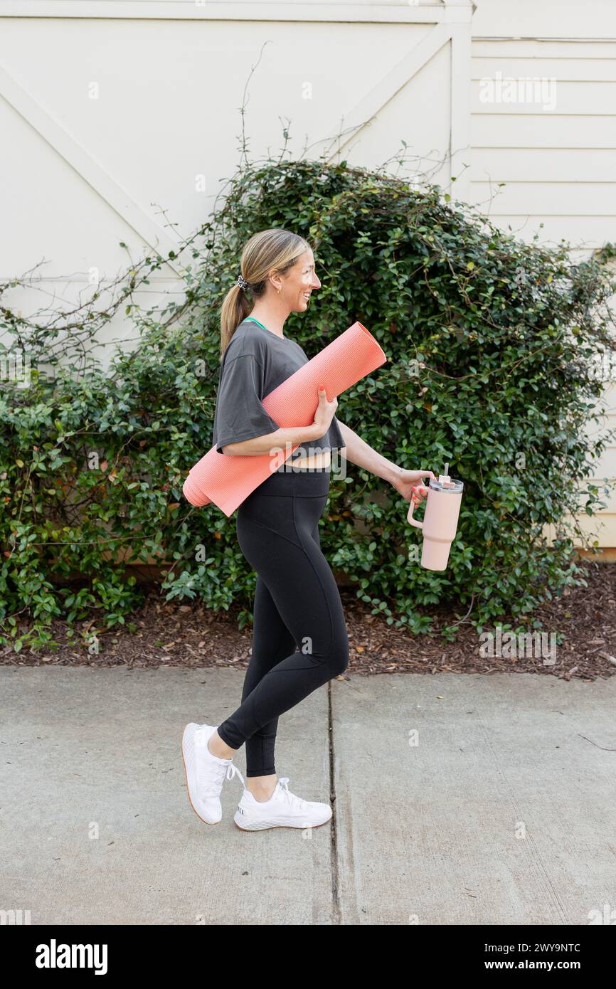 Femme souriante avec tapis de yoga à l'extérieur Banque D'Images