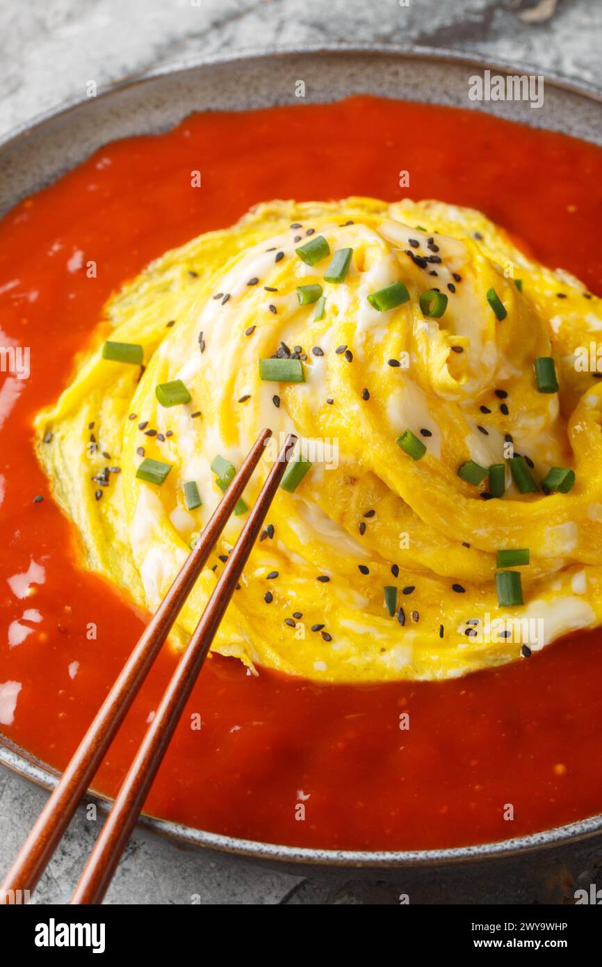 Omelette omelette omelette omurice Tornado avec riz et sauce piquante gros plan sur l'assiette sur la table. Vertical Banque D'Images
