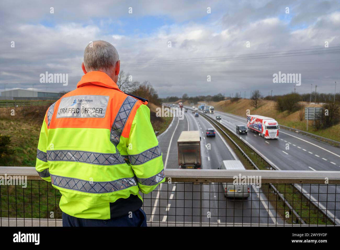 Highways England officier de la circulation observant le flux de la circulation depuis un pont sur l'A1M, Angleterre. Banque D'Images