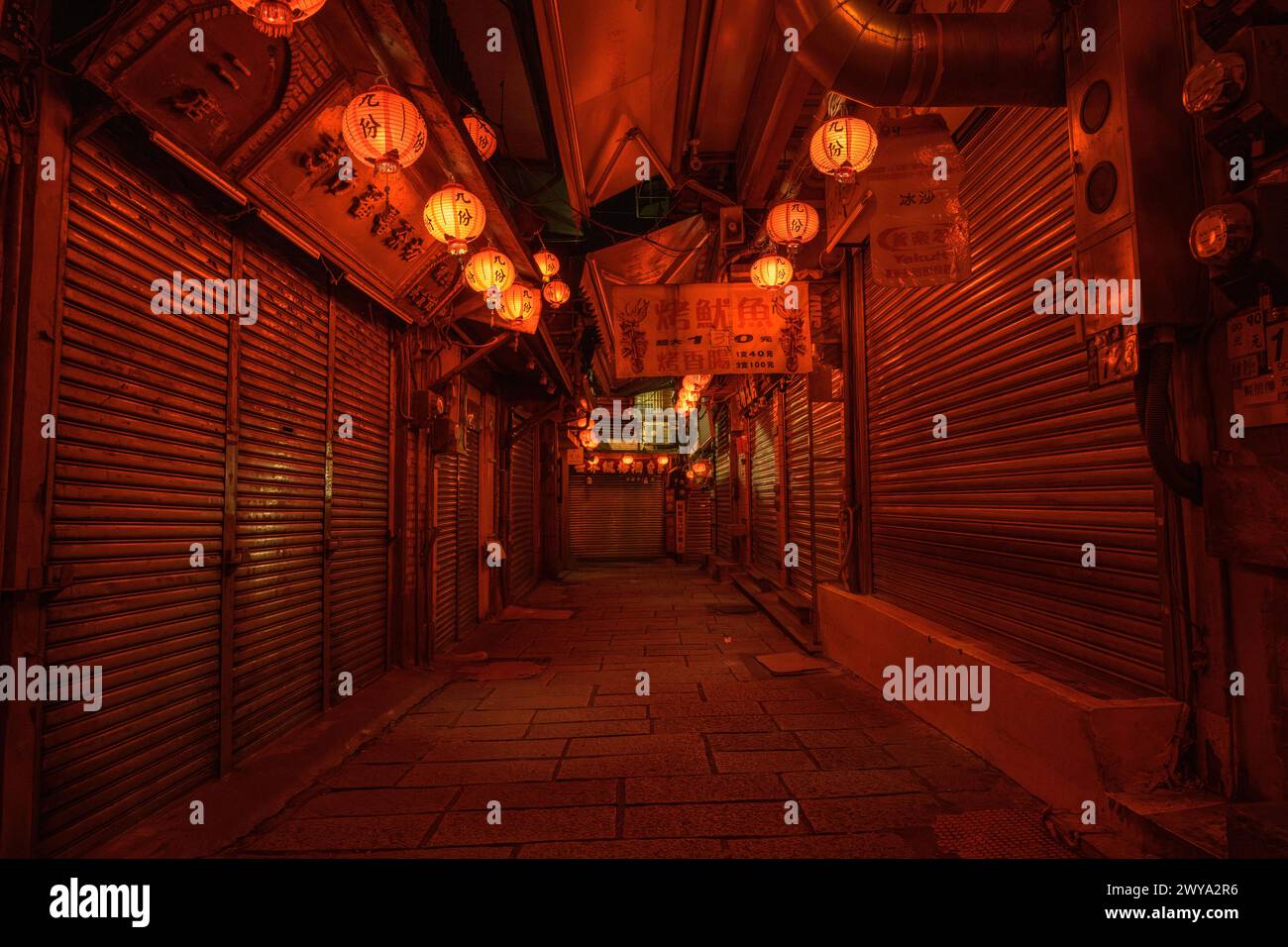 Une ruelle étroite et calme décorée de lanternes menant à un marché traditionnel avec ses boutiques fermées dans les rues de Jiufen Banque D'Images