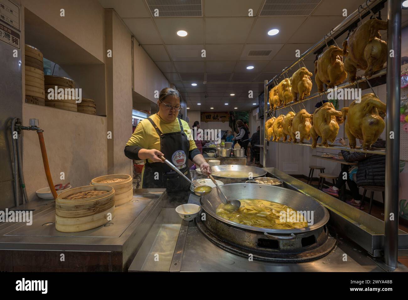 Une femme servant des plats traditionnels chinois dans un étal de nourriture dans les rues de Jiufen Banque D'Images