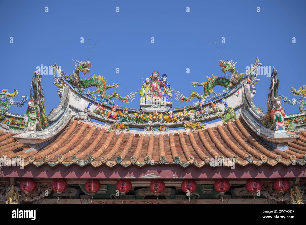 Un affichage vif des décorations traditionnelles chinoises de toit de temple avec des créatures mythiques contre un ciel bleu clair dans le temple de Mazu Banque D'Images
